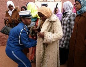 A policewoman, left, searches women wishing to attends Algerian