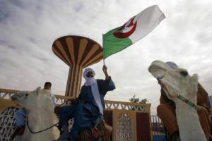 A man holds an Algerian flag as he rides