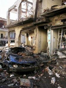 A destroyed car and damaged building are seen at