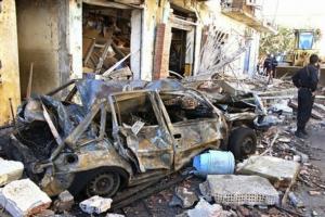 A destroyed car and damaged building are seen at