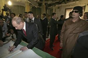 Russian President Vladimir Putin (L) signs the guest book