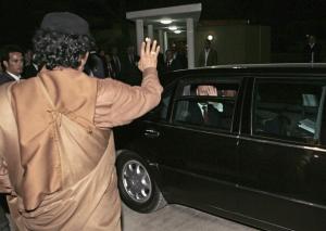 Russian President Vladimir Putin (R) waves at Libyan leader