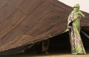 A Saharawi woman stands beside a traditional tent at