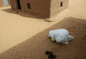 A Sahrawi woman prays outside her house at Dakhla's