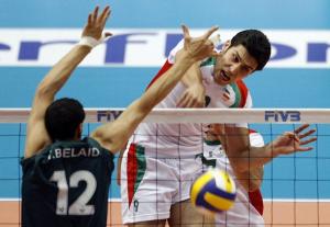 Iran's Alireza Nadi (R) spikes the ball past Algeria's
