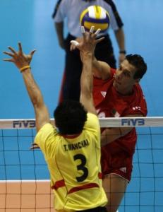 Algeria's Mahdjoubi Toufik (R) spikes the ball past Thailand's