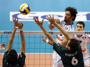 Italy's Vigor Bovolenta (C) spikes the ball against Algeria's