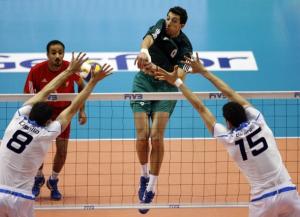 Algeria's Chikhi Mohamed (C) spikes the ball against Italy's