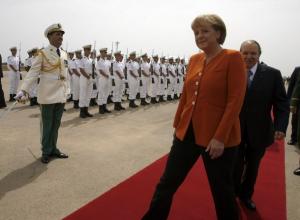 Algeria's President Abdelaziz Bouteflika walks behind German Chancellor Angela