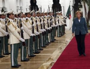 German Chancellor Angela Merkel walks past the Algerian national