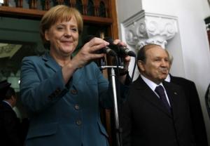 German Chancellor Angela Merkel (L) adjusts a microphone before