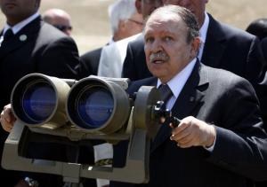 Algeria's President Abdelaziz Bouteflika stands next to a giant