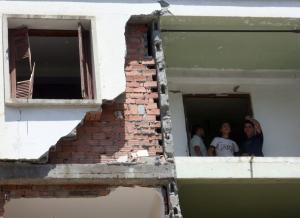 People look from a damaged building at the site