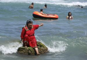 A woman gestures on the Little Paradise beach outskirt