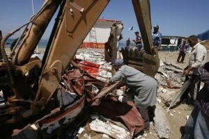 Municipal workers clear away rubble from the site of