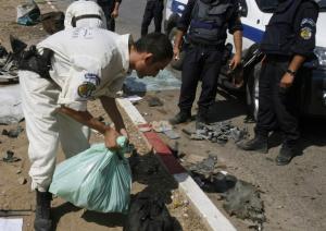 A bomb disposal expert collects evidence at the site