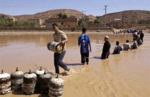 Residents transport gas bottles across a river in the
