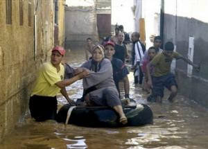 Rescue workers help residents in a flooded street, in