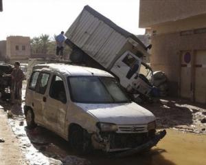 Residents stand by damaged vehicles in a flooded street