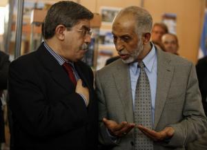 Algeria's Prime Minister Ahmed Ouyahialistens (L) talks to former